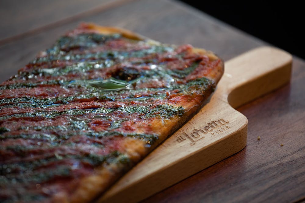 a slice of pizza sitting on top of a wooden cutting board