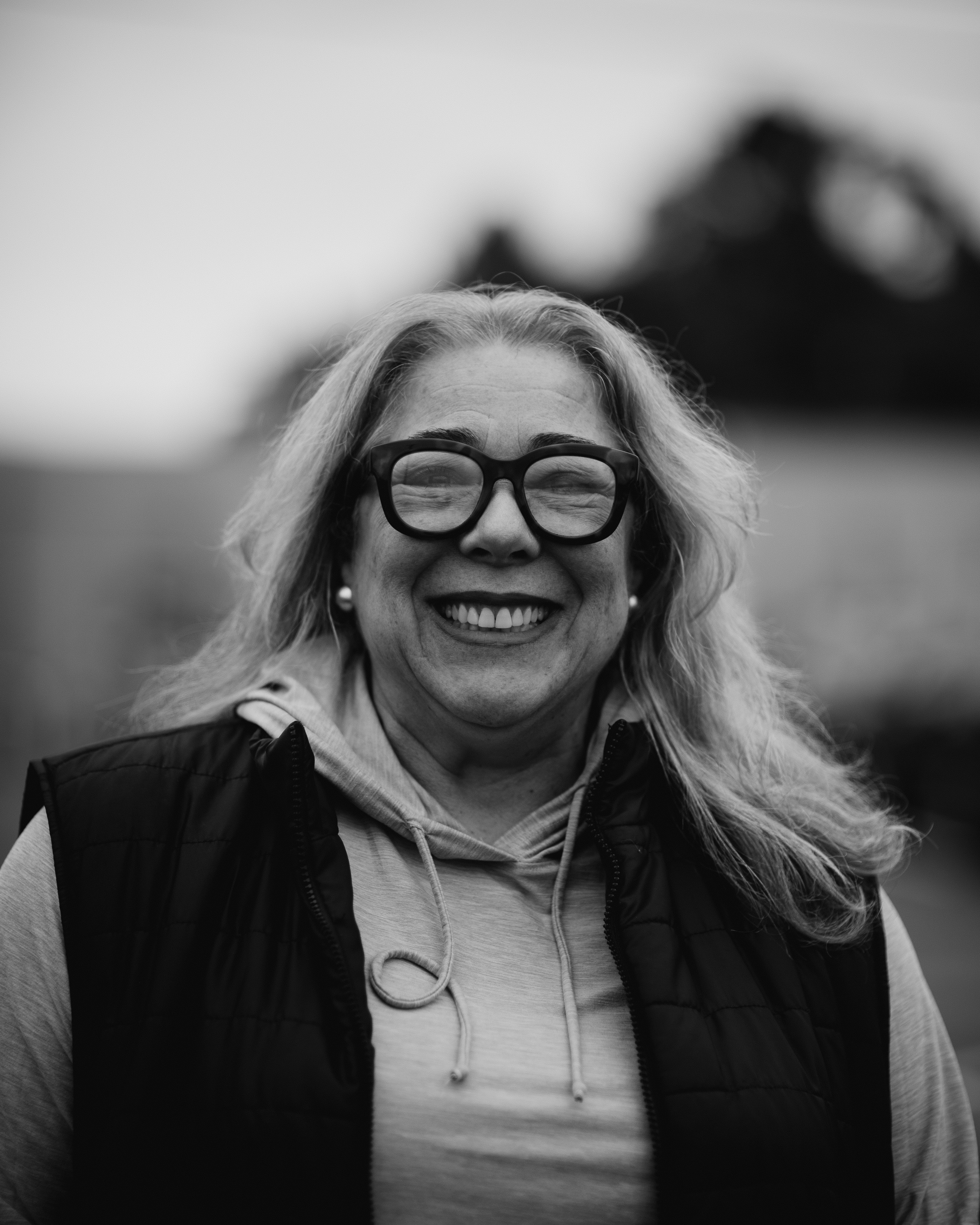a woman wearing glasses and a vest smiling