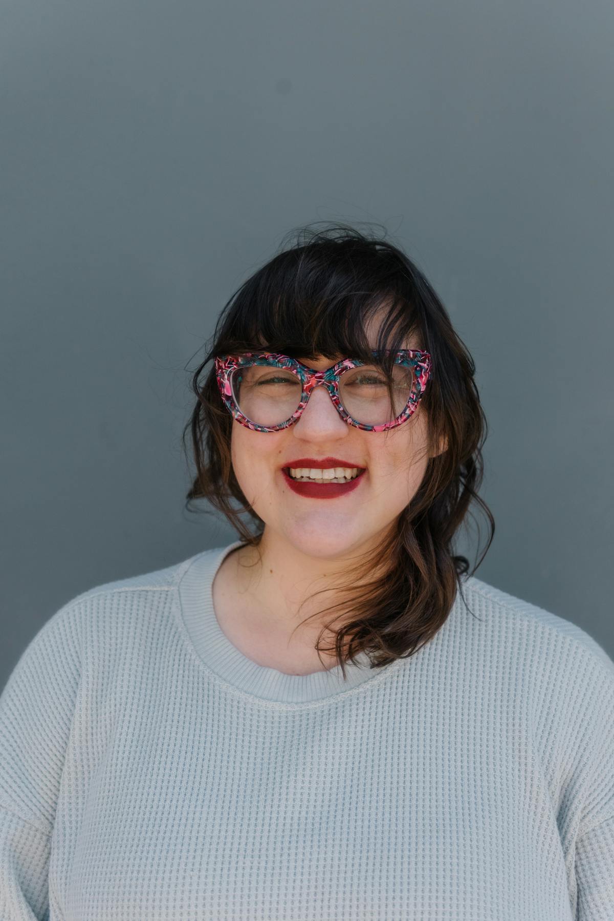 a person wearing glasses and smiling at the camera