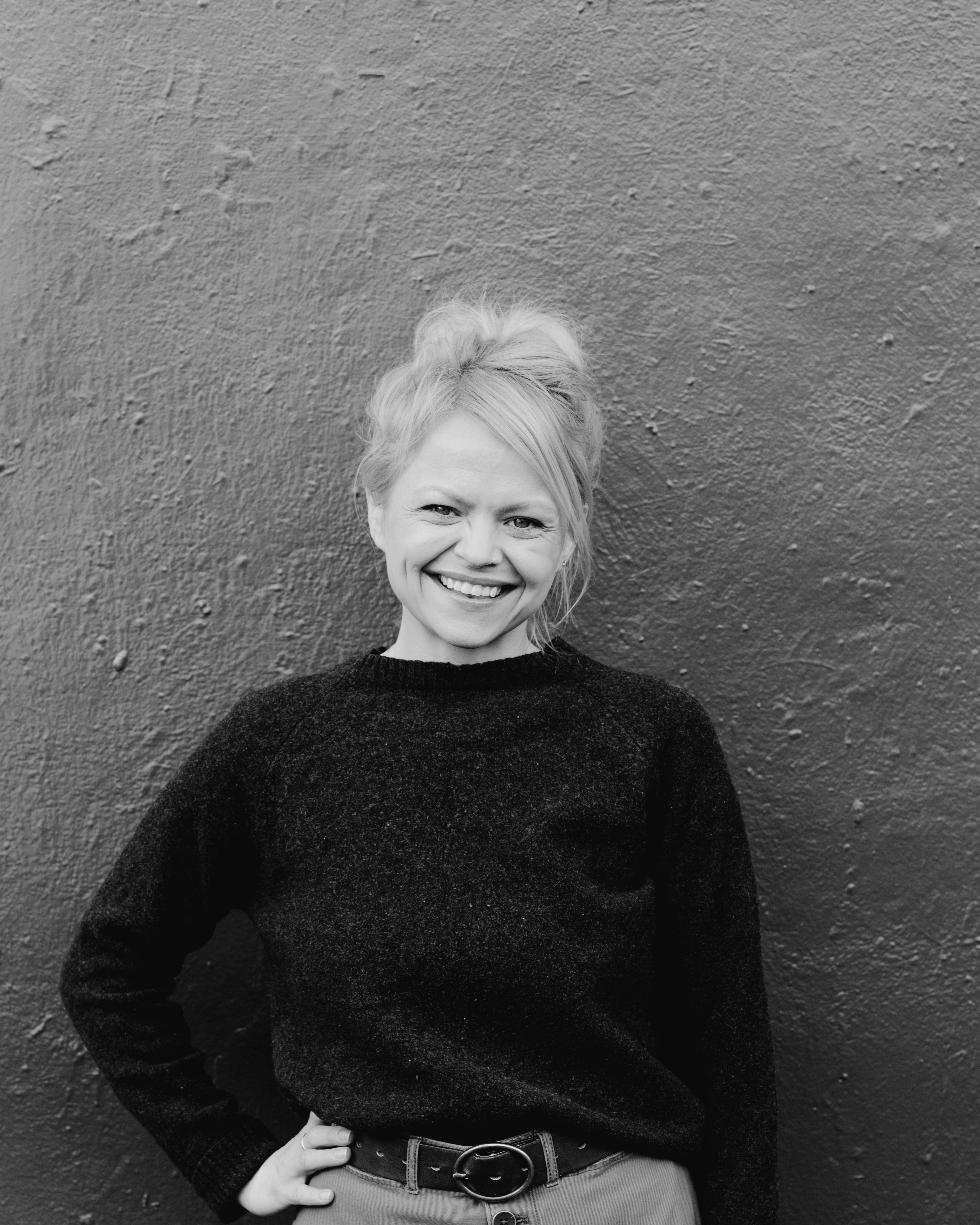 a woman smiling in front of a wall