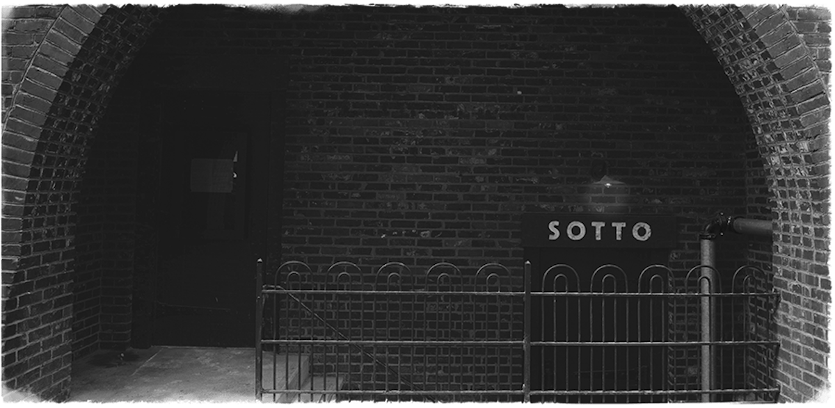 a black sign with white text on a brick building