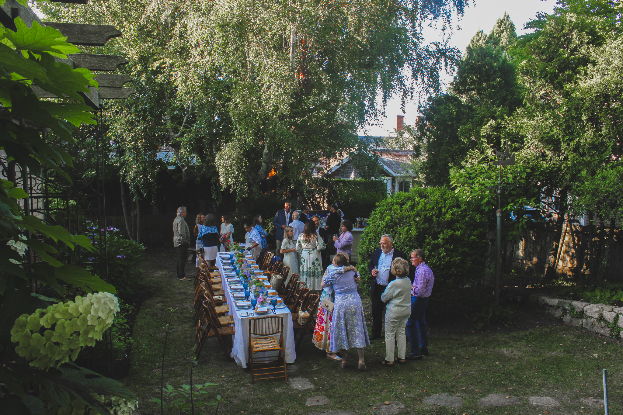 a group of people standing around a table with food and chairs
