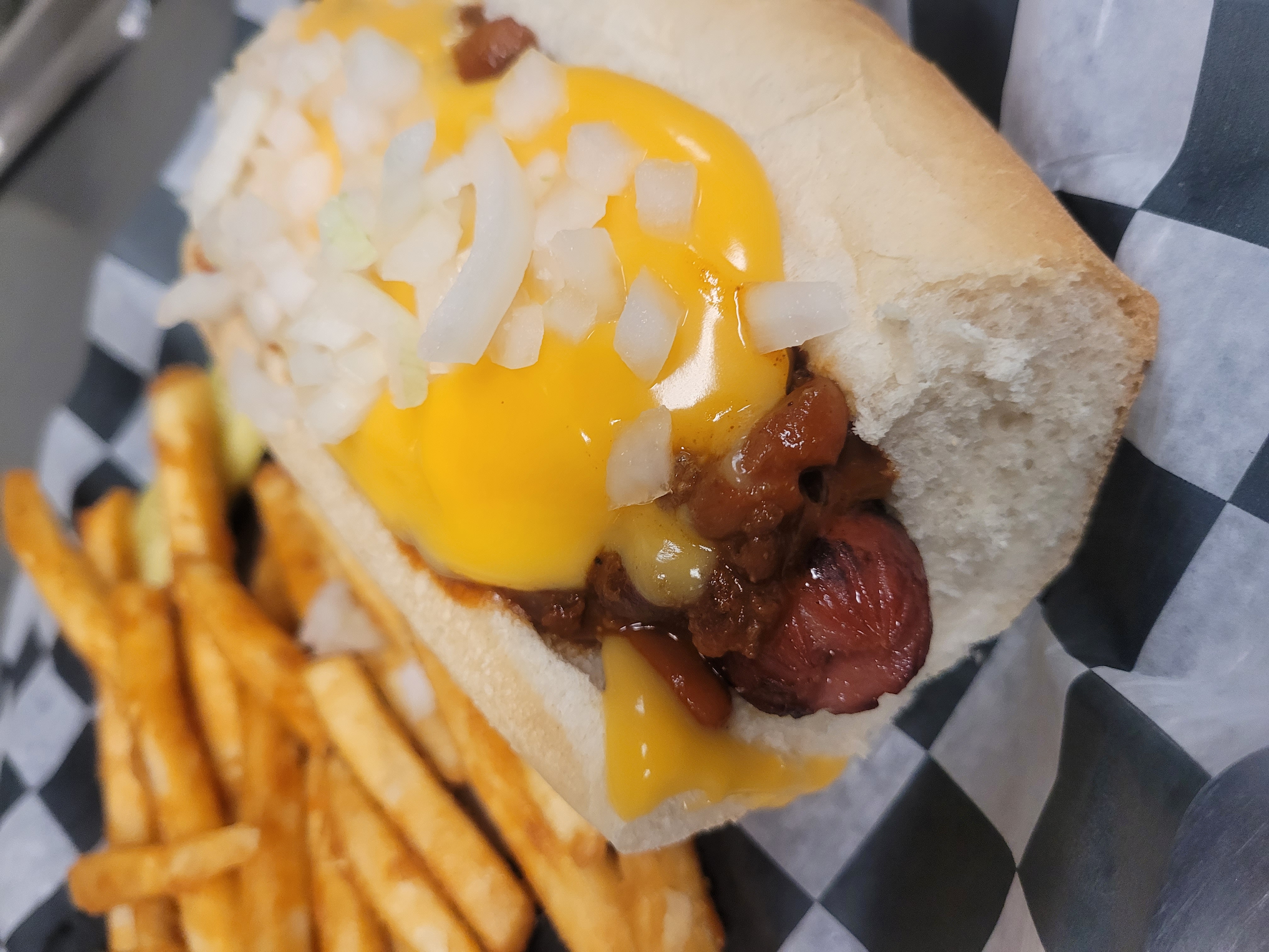 a hot dog on a bun next to some fries