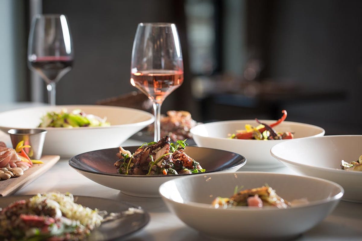 a plate of food and glasses of wine on a table