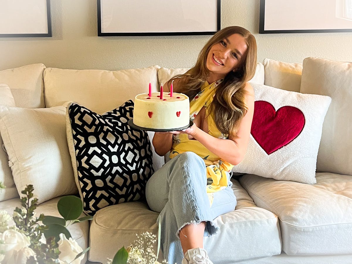 a woman sitting on a sofa holding a white cake with red hearts