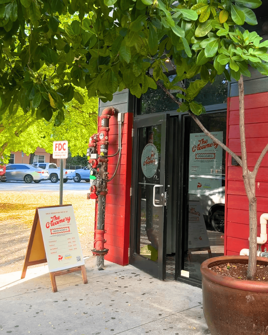 a red building with a sign and a tree