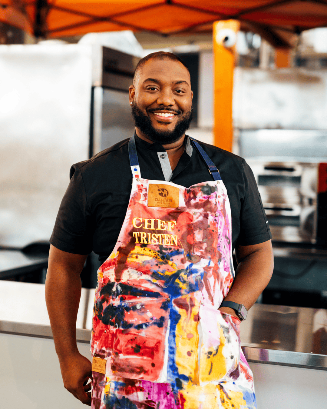 Chef Tristen Epps-Long standing in the kitchen wearing a chef apron labeled ‘Chef Tristen’.