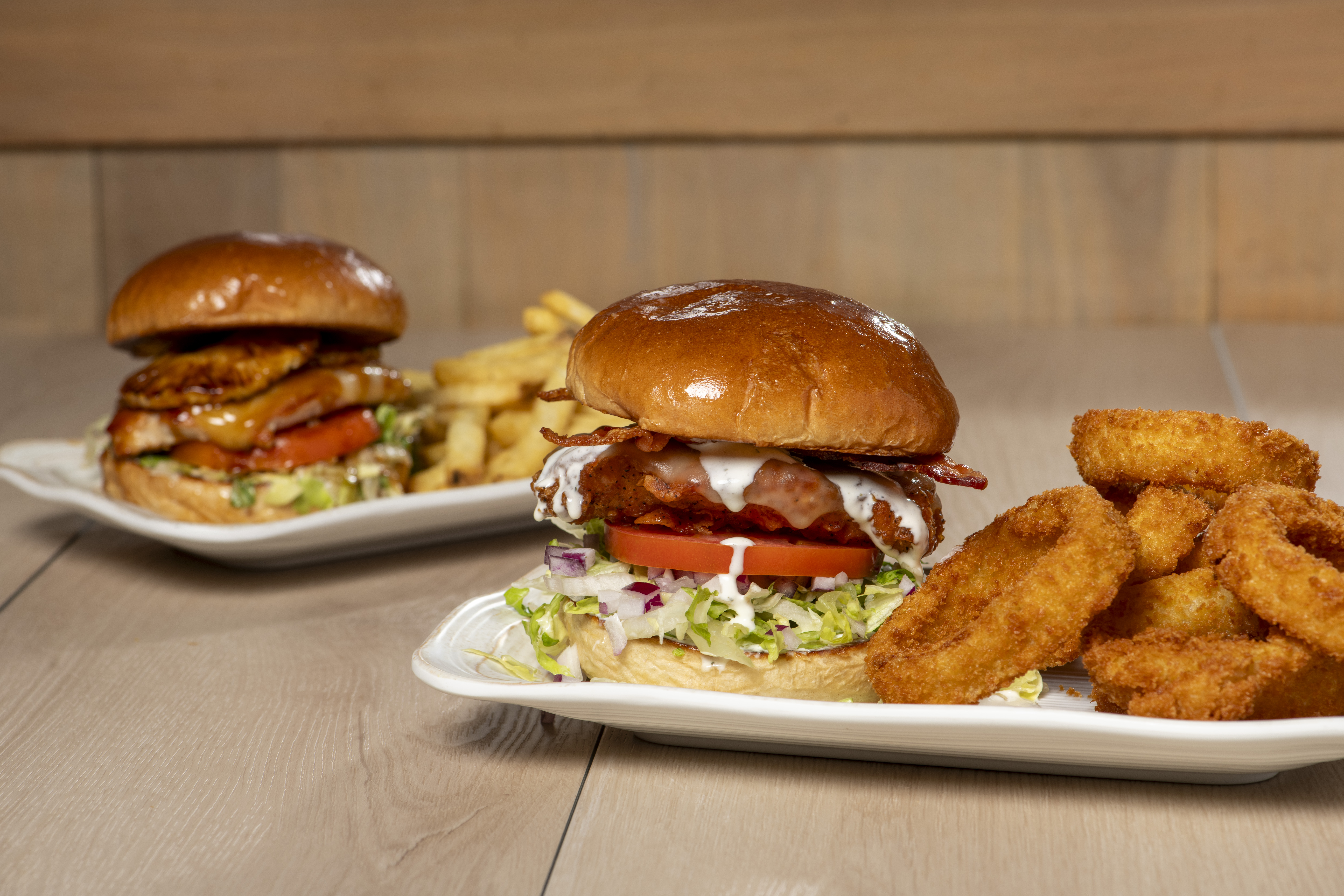 Fried chicken sandwich with bacon and onion rings on the side