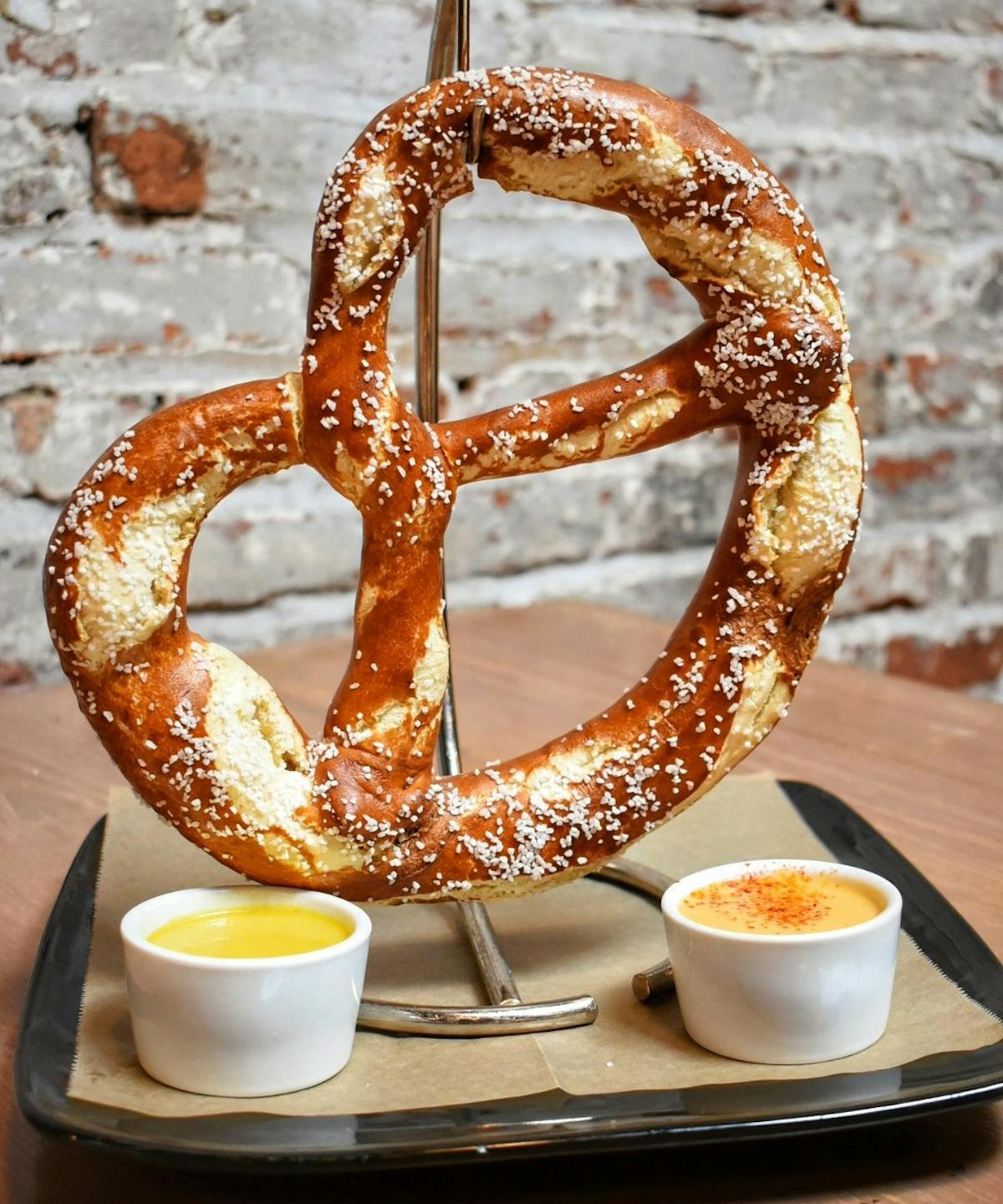 a big pretzel on a hook with dipping sauces