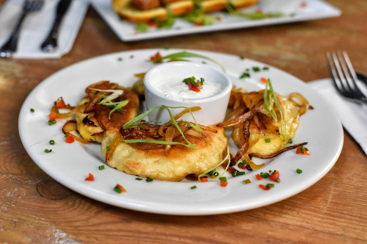 a plate of pierogies with sour cream
