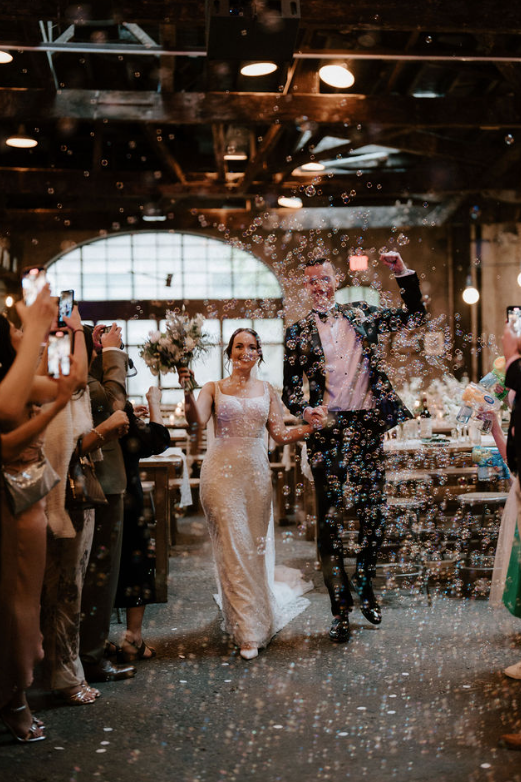 a man and woman walking down a aisle with bubbles