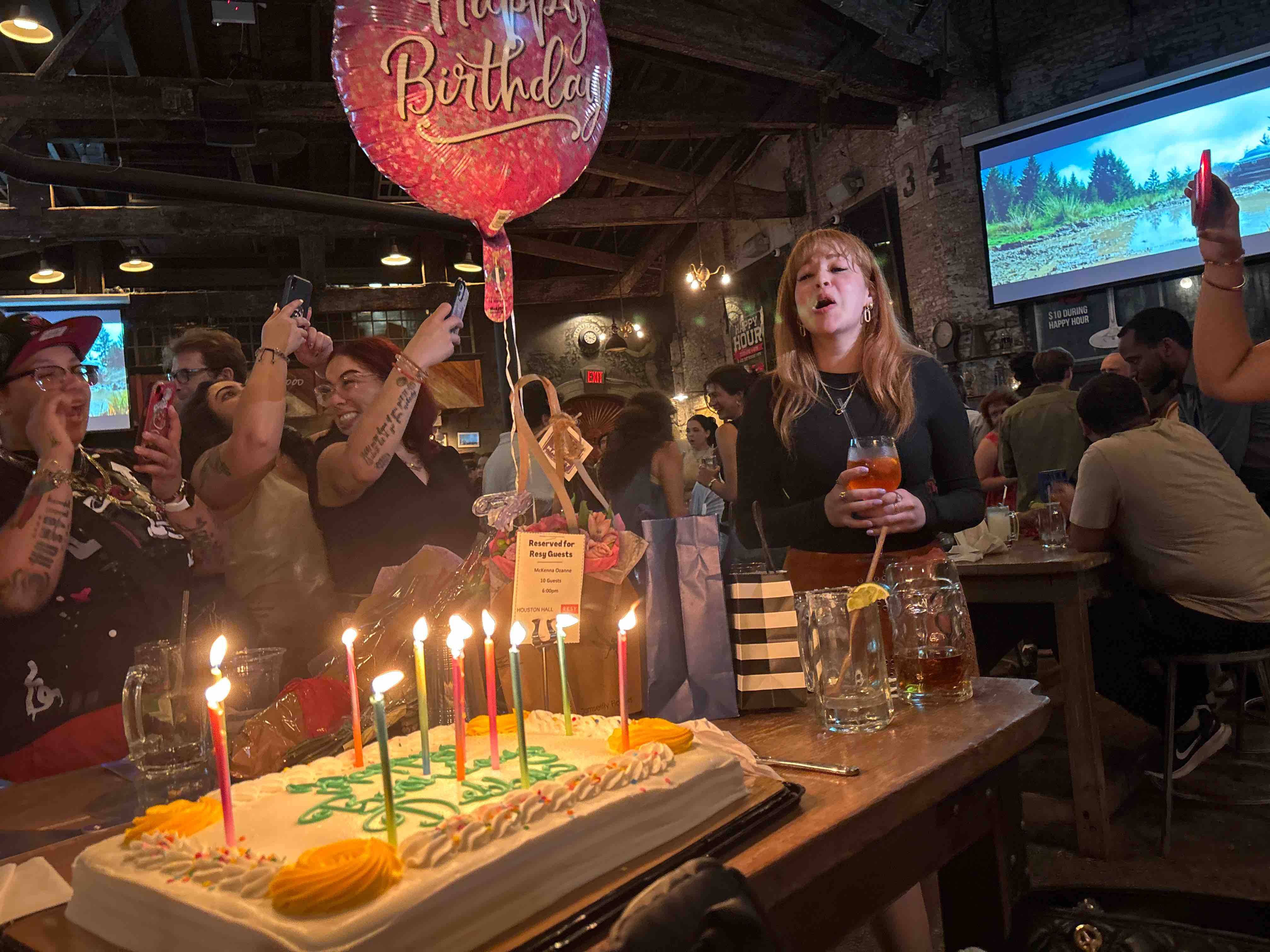 a group of people in front of a birthday cake with lit candles