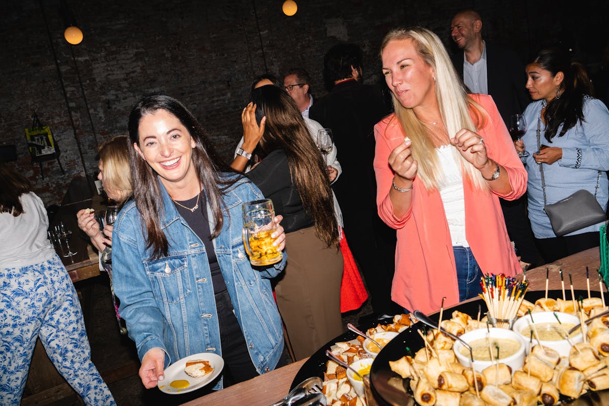 two people standing in front of a table with food