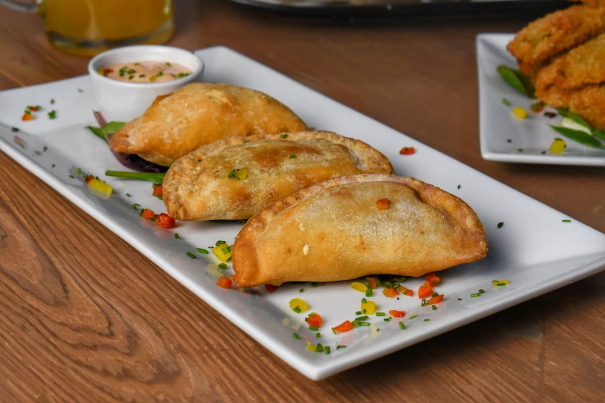 a plate with three empanadas on a table