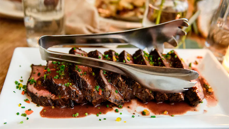 Steak on a plate with serving tongs at our party venue near Greenwich Village, New York City.