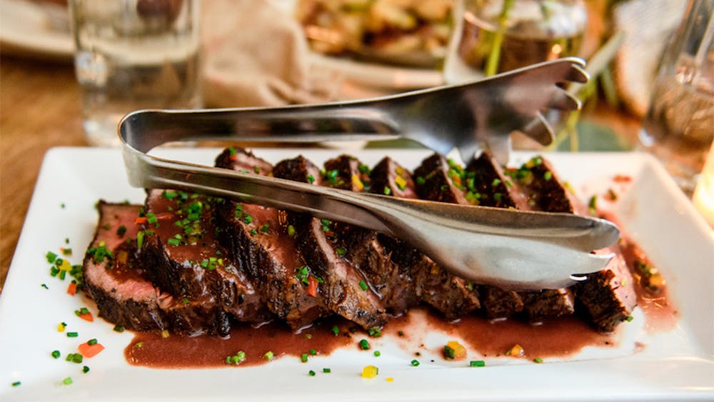 Steak on a plate with serving tongs at our party venue near Hudson Square, New York City.
