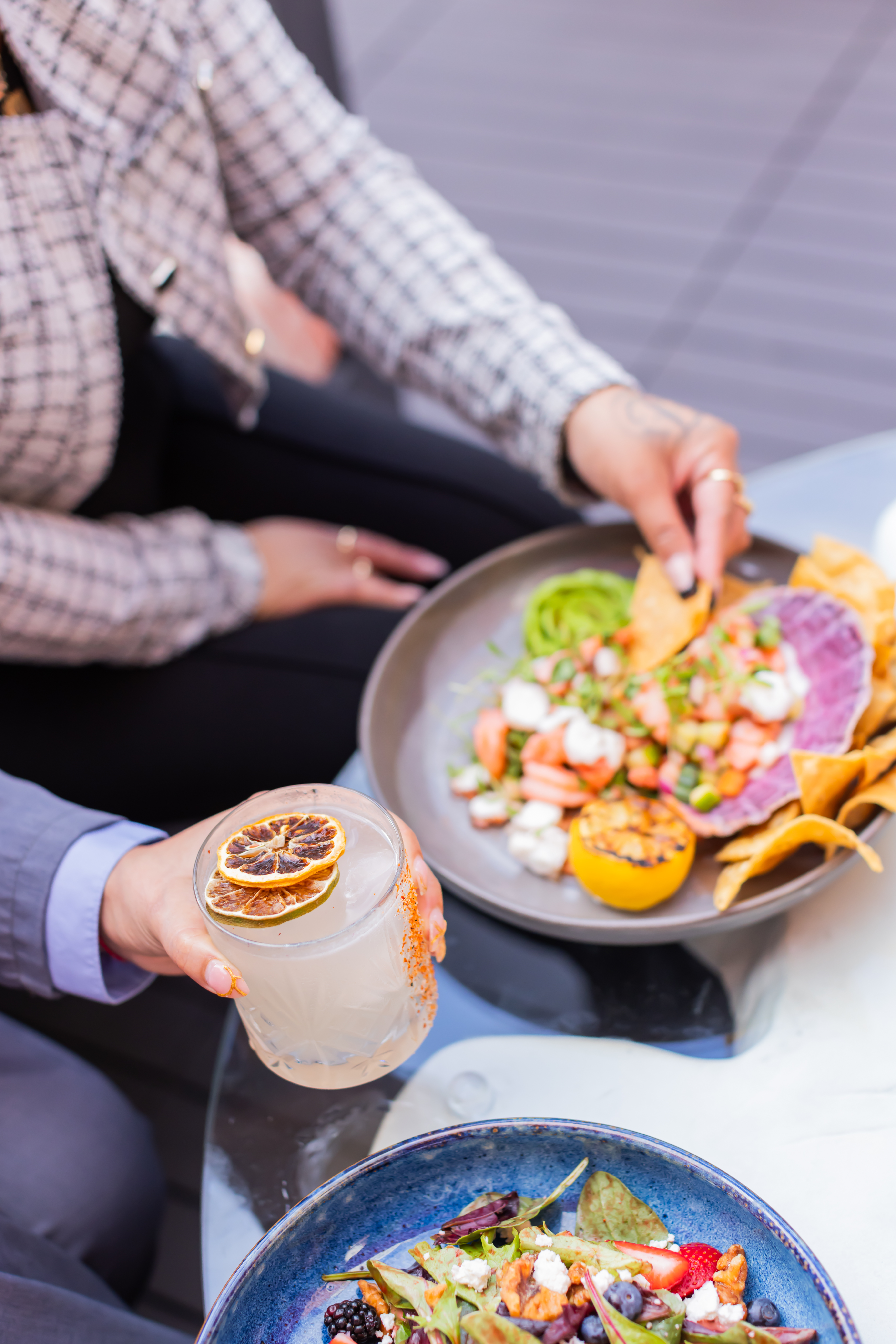 a person holding a drink and a plate of food