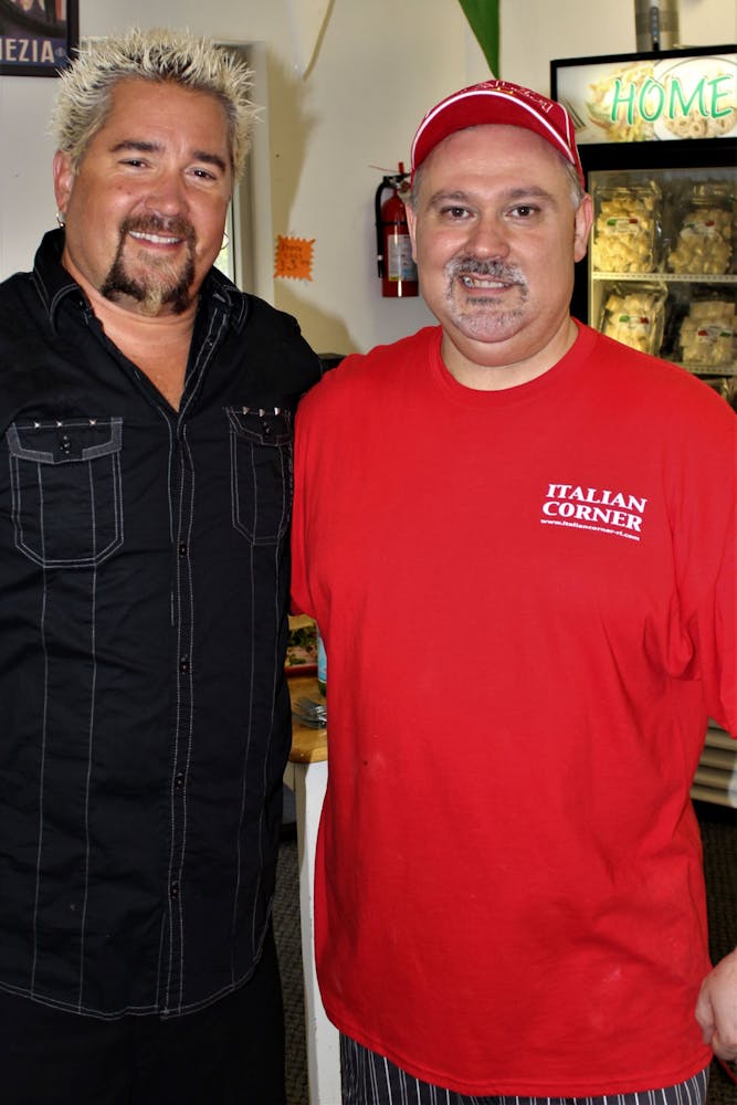 a man standing in front of Guy Fieri et al. posing for the camera