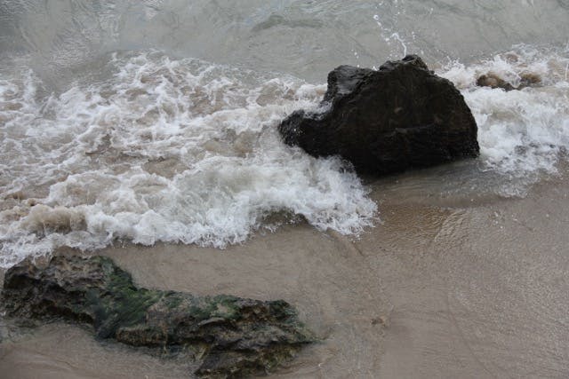 a person riding a wave on top of a rock