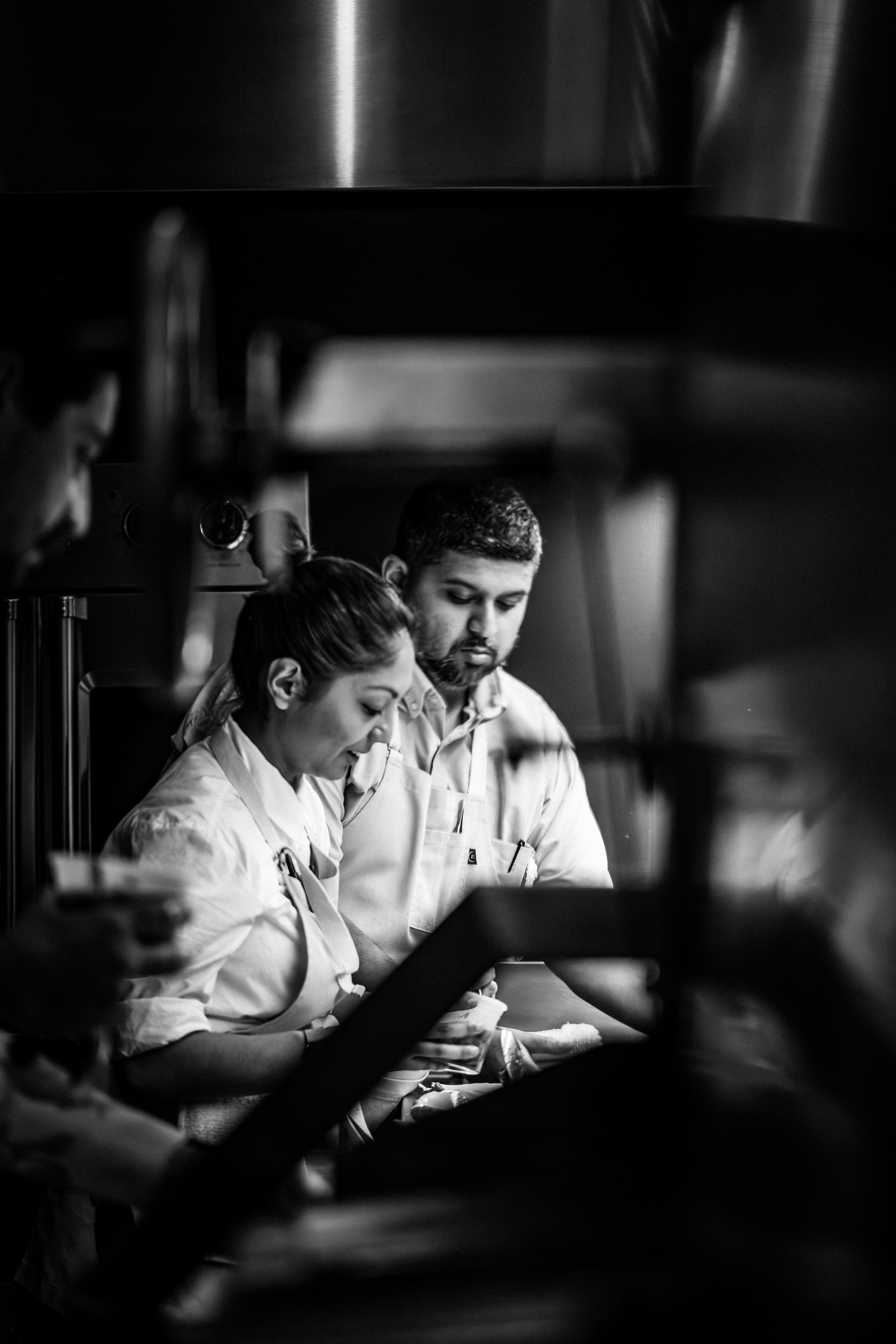 black and white image of chef yan and chef reena cooking