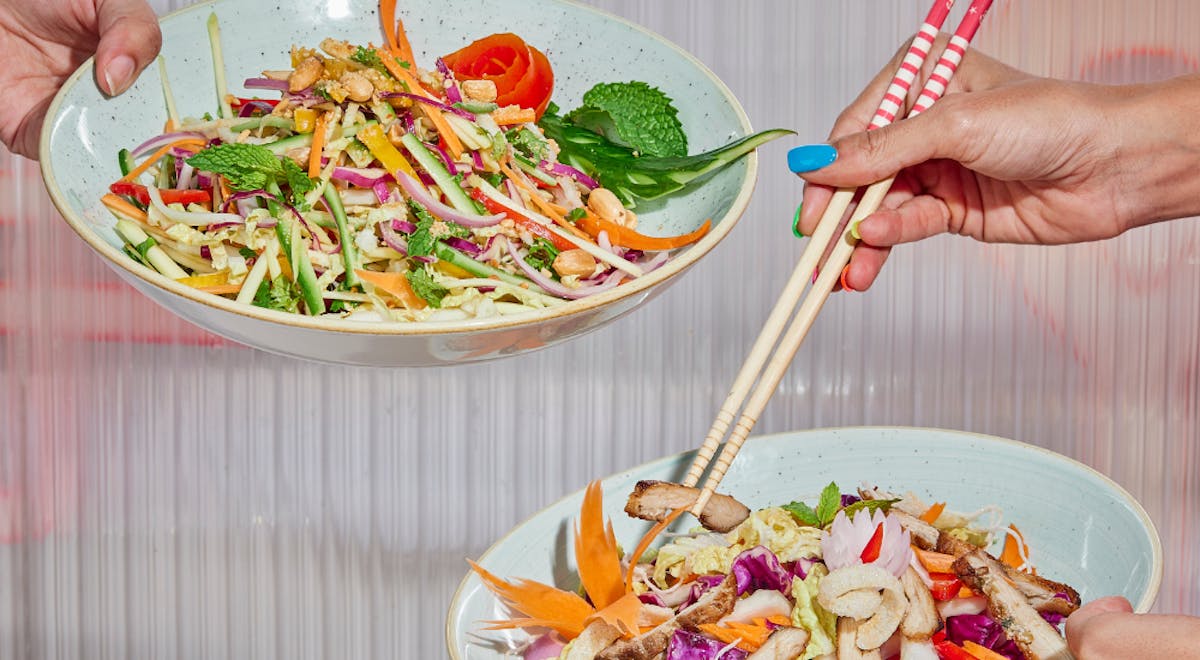 a person holding a bowl of salad