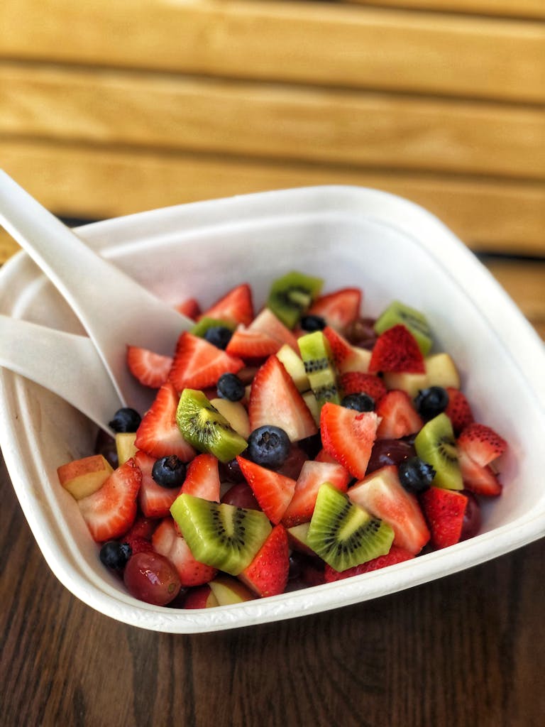 a bowl of fruit sitting on top of a plate of food