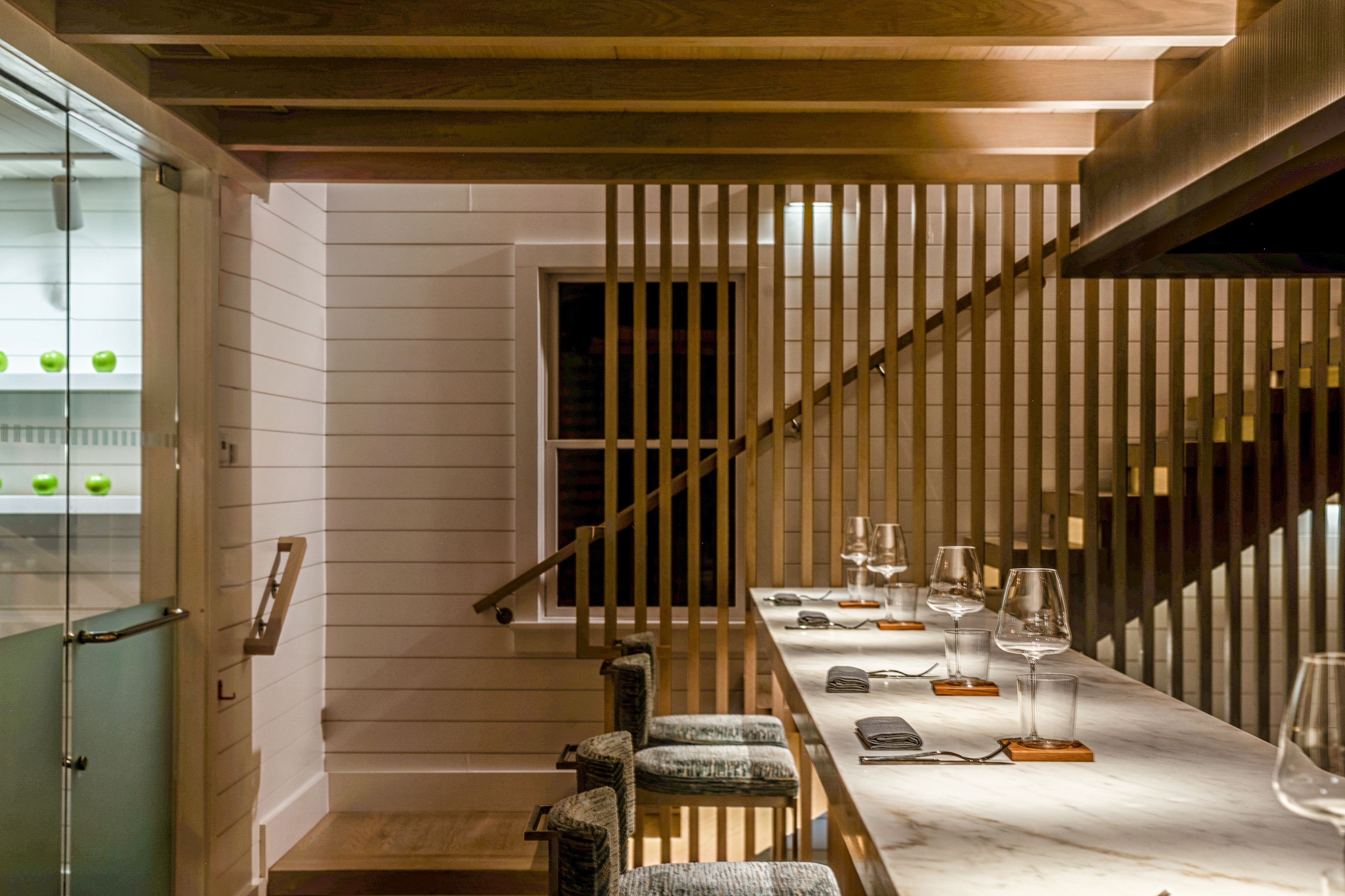 a table with wine glasses and chairs in a room with a staircase