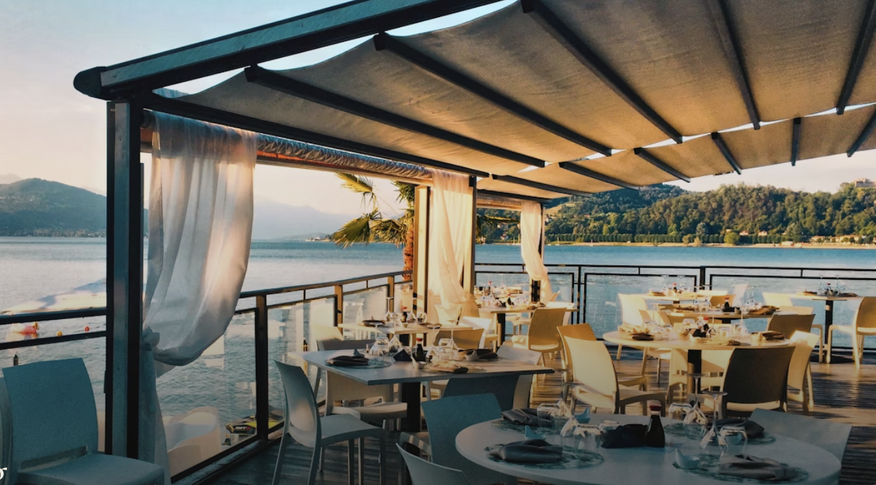 a restaurant with tables and chairs on a deck overlooking a body of water