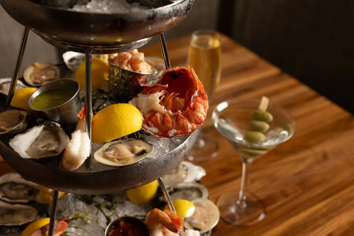 a triple decker seafood tower featuring clams, oysters, lobster served with a dirty martini