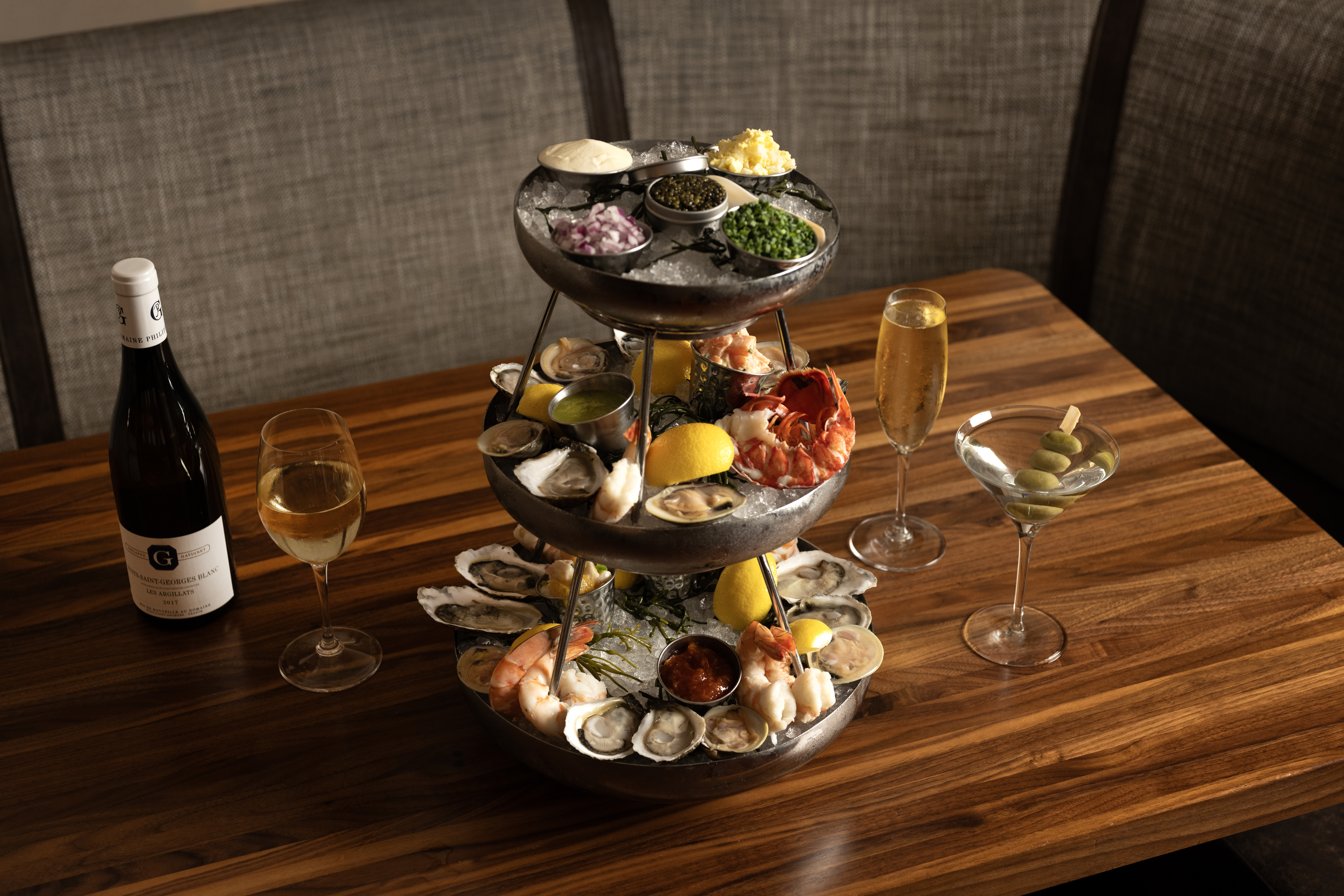 a triple decker seafood tower featuring clams, oysters, lobster served with a dirty martini