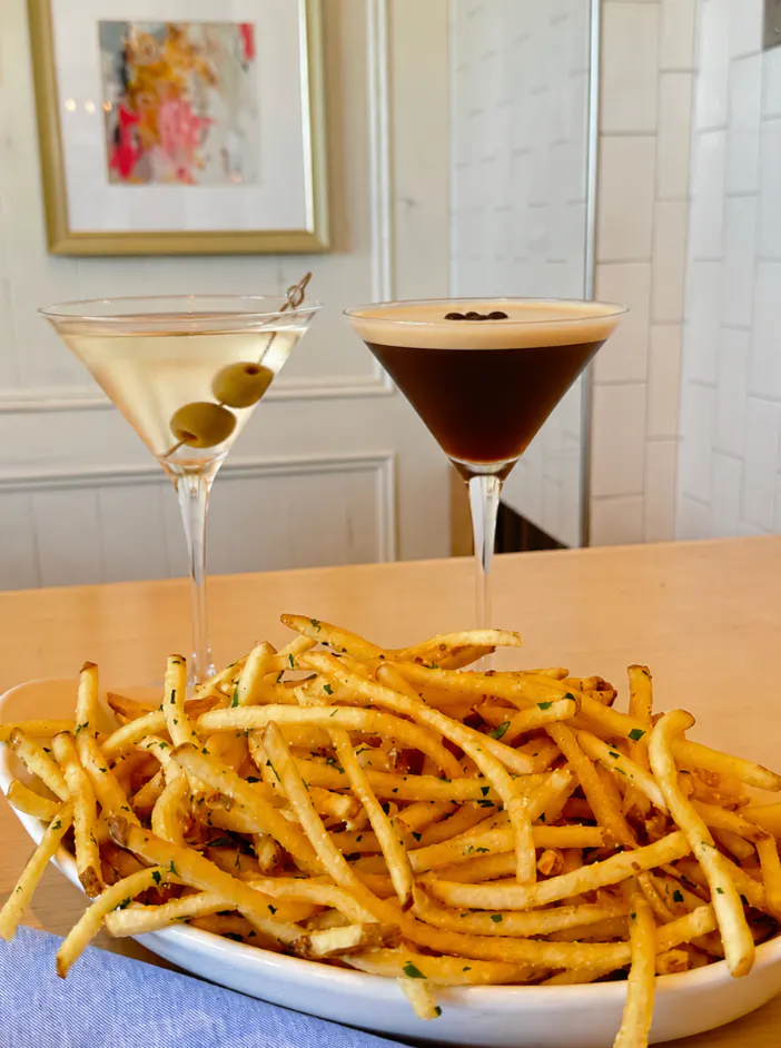 girl dinner in henderson featuring martinis, fries, pasta, and caesar salad