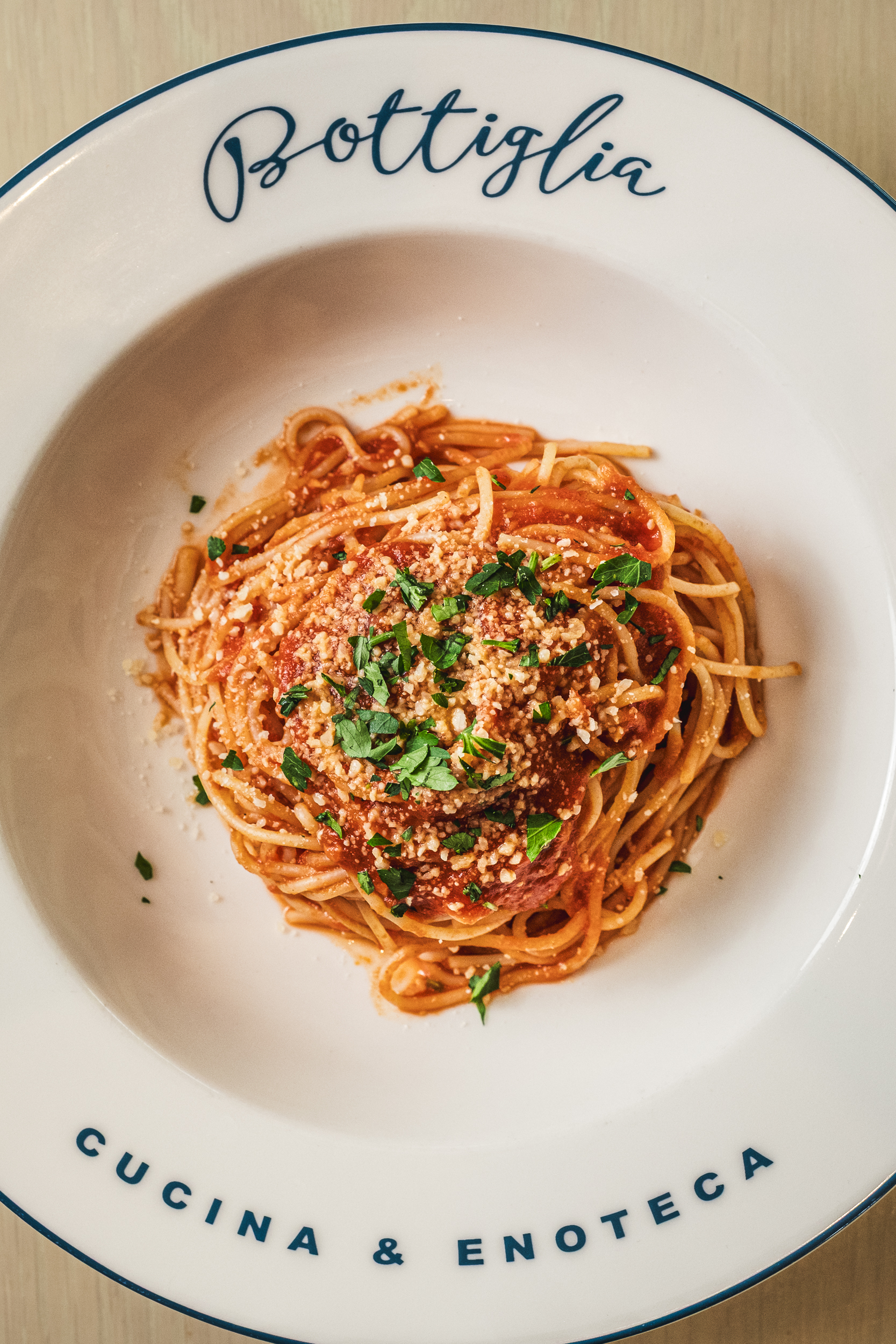 Bolognese pasta topped with parmesan and basil on a white ceramic plate for a must try dish at this henderson italian