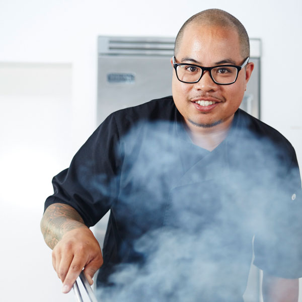 a man wearing glasses and a black shirt holding a pair of tongs