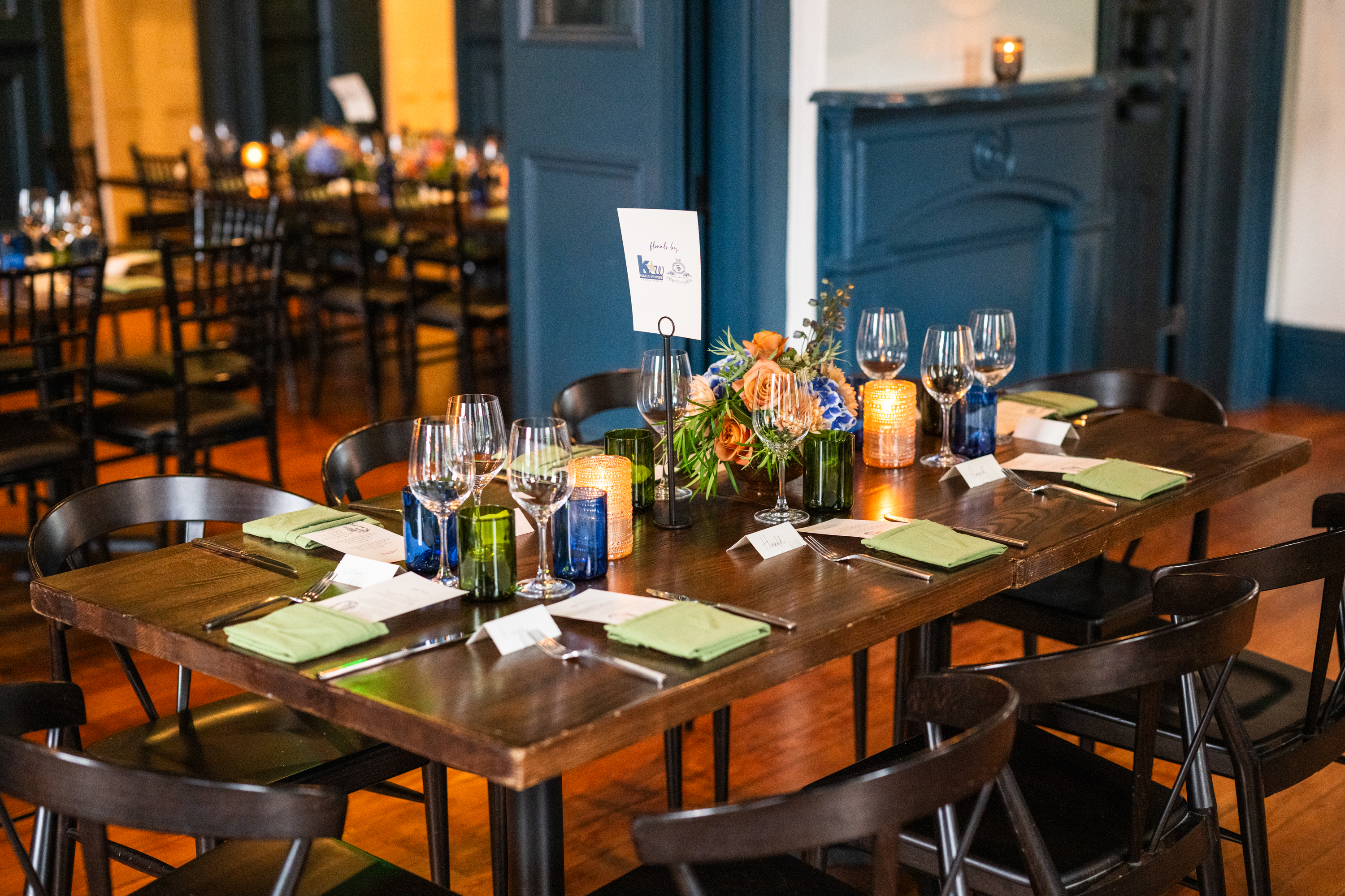 a dining table set for a meal with flowers and candles