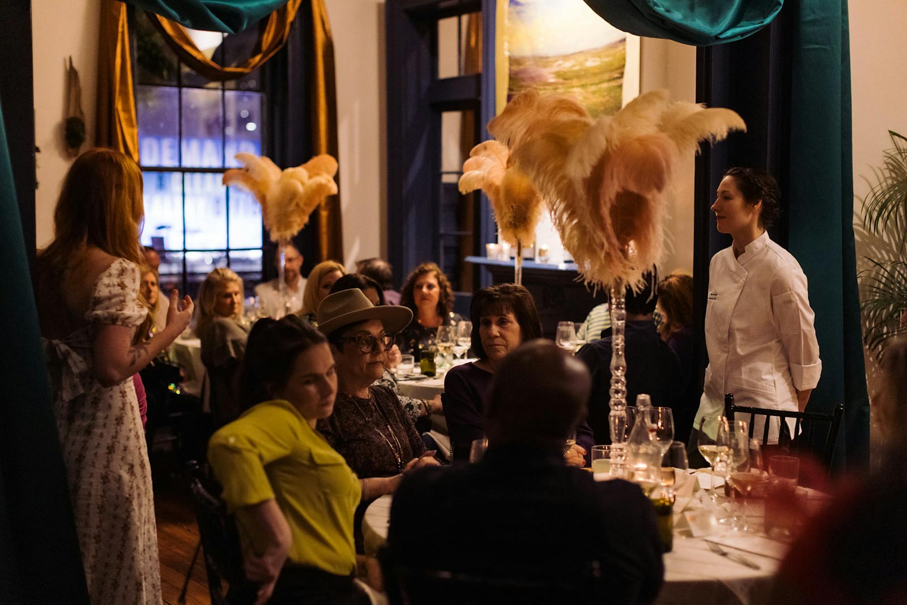 A wide room featuring groups of people seated at tables, engaged in various activities and conversations