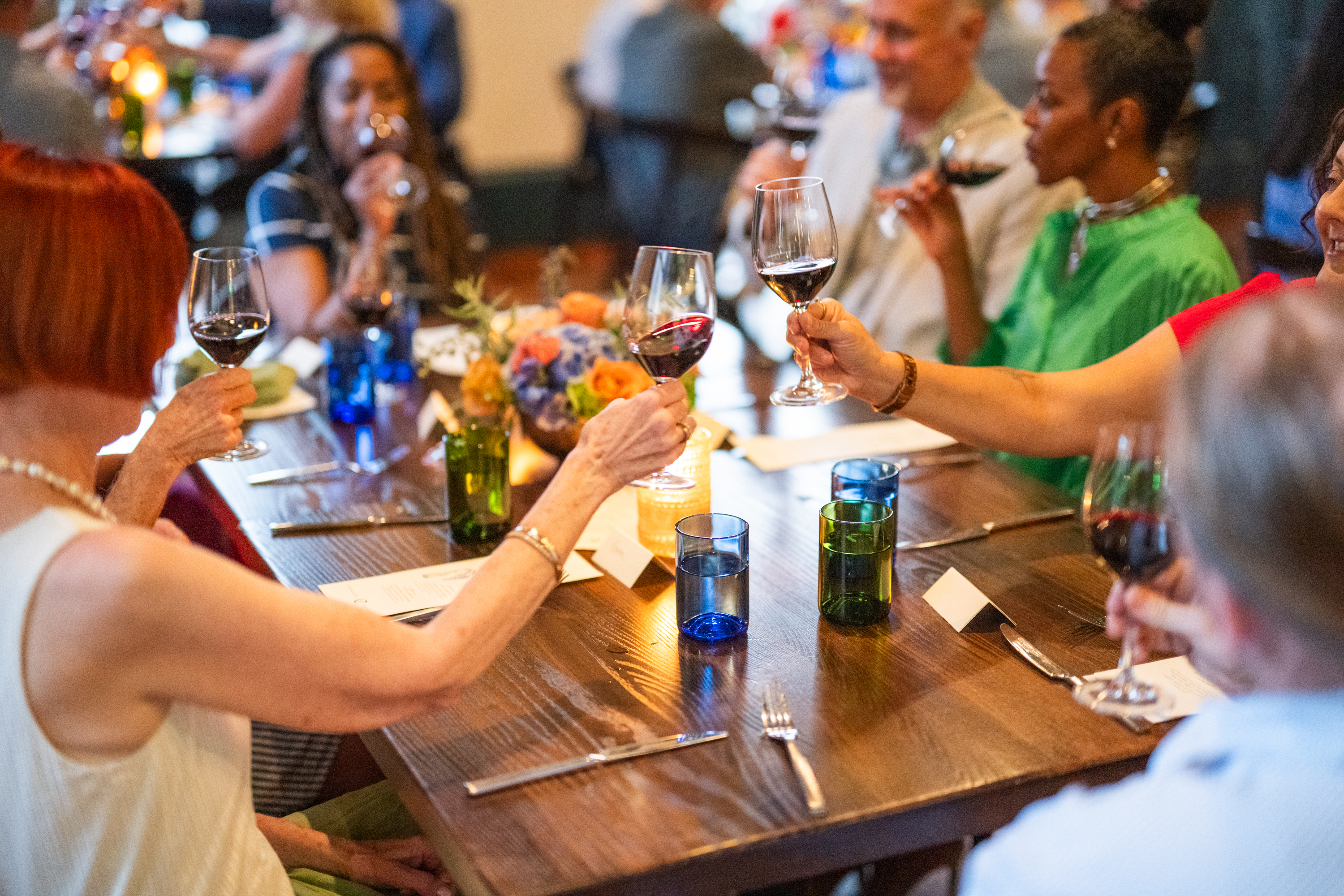 A group of people sitting at a table, toasting with wine glasses.