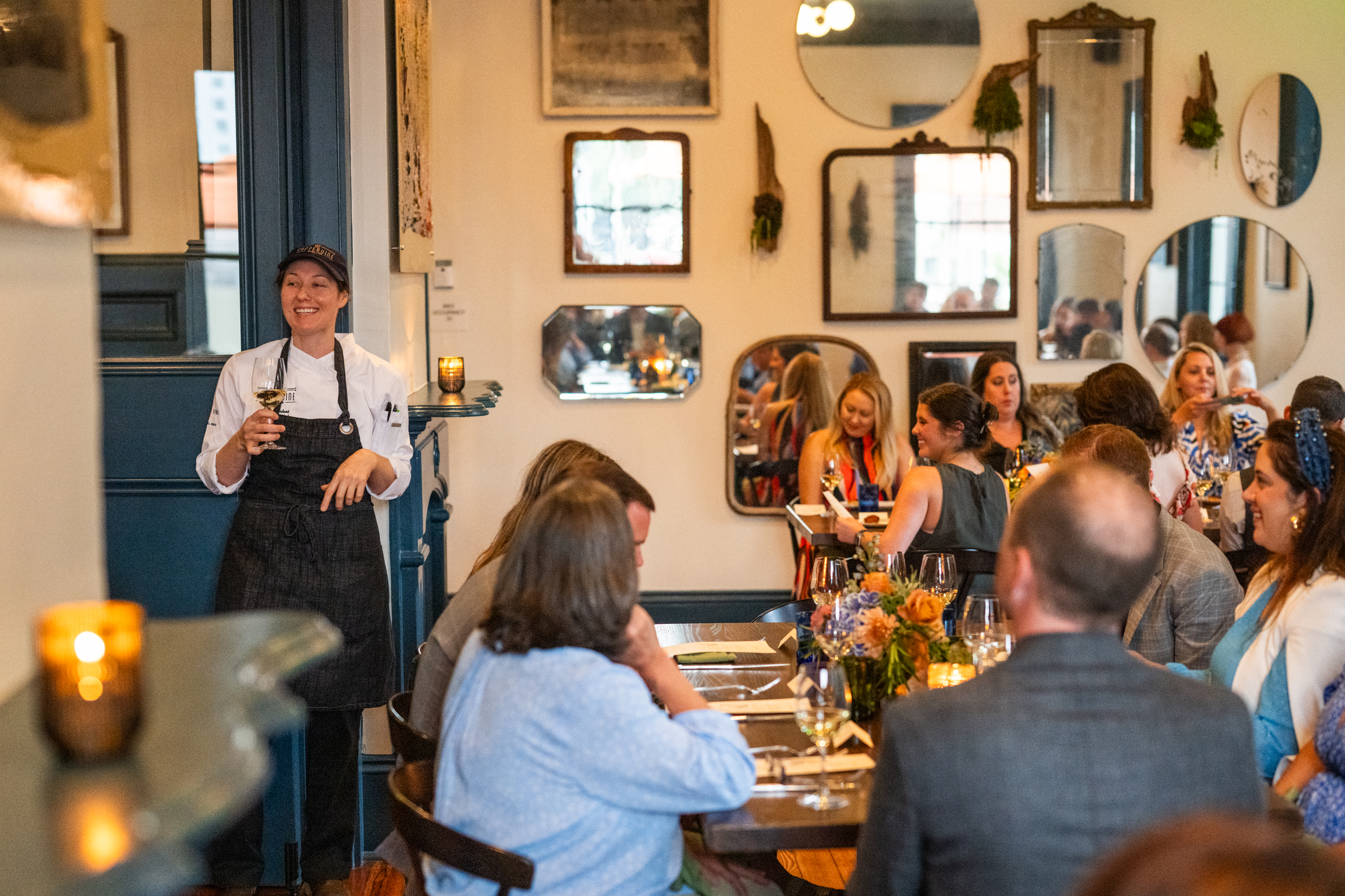 a group of people sitting at a table in a restaurant with a server standing nearby