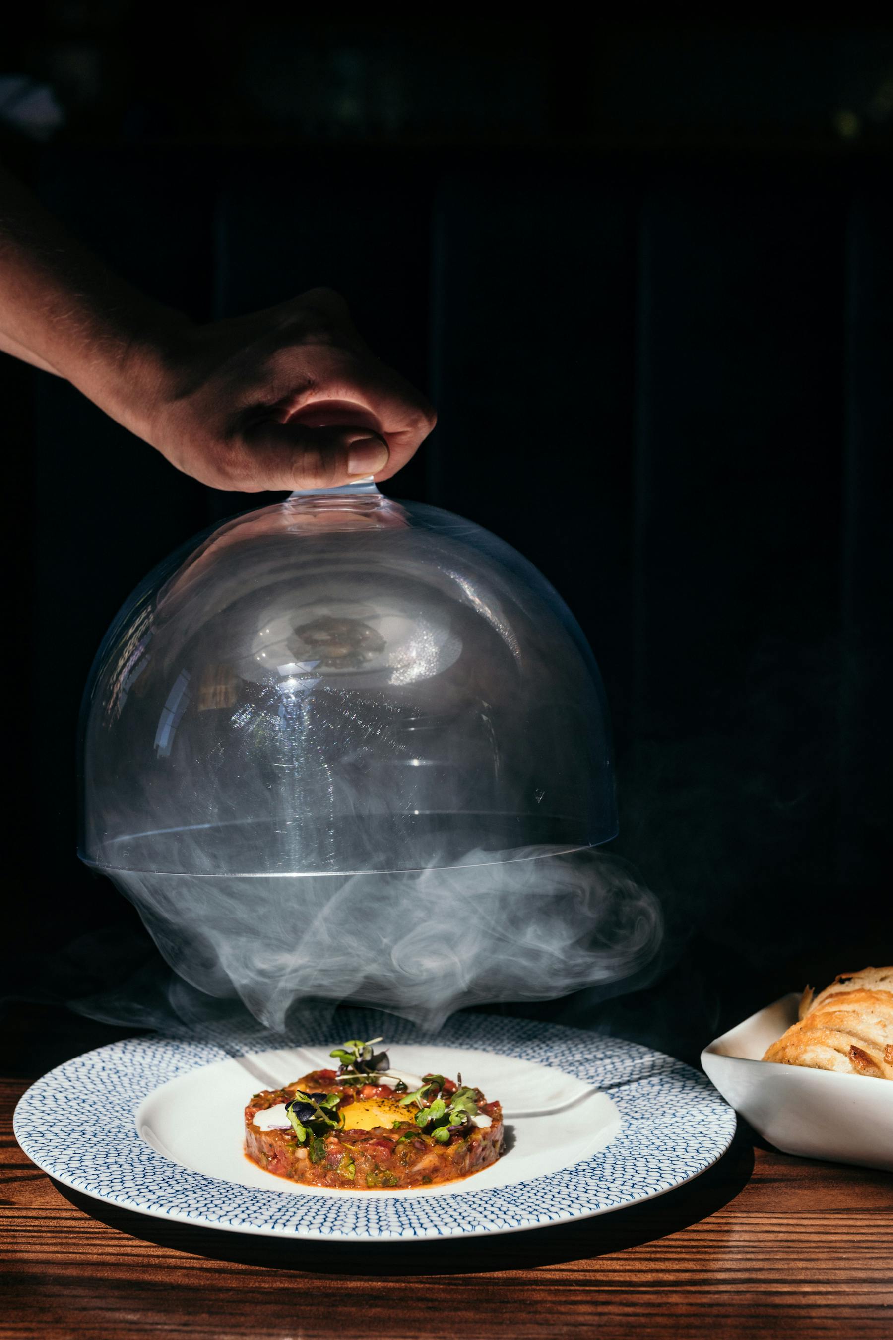 A hand lifts a plate of food over a table