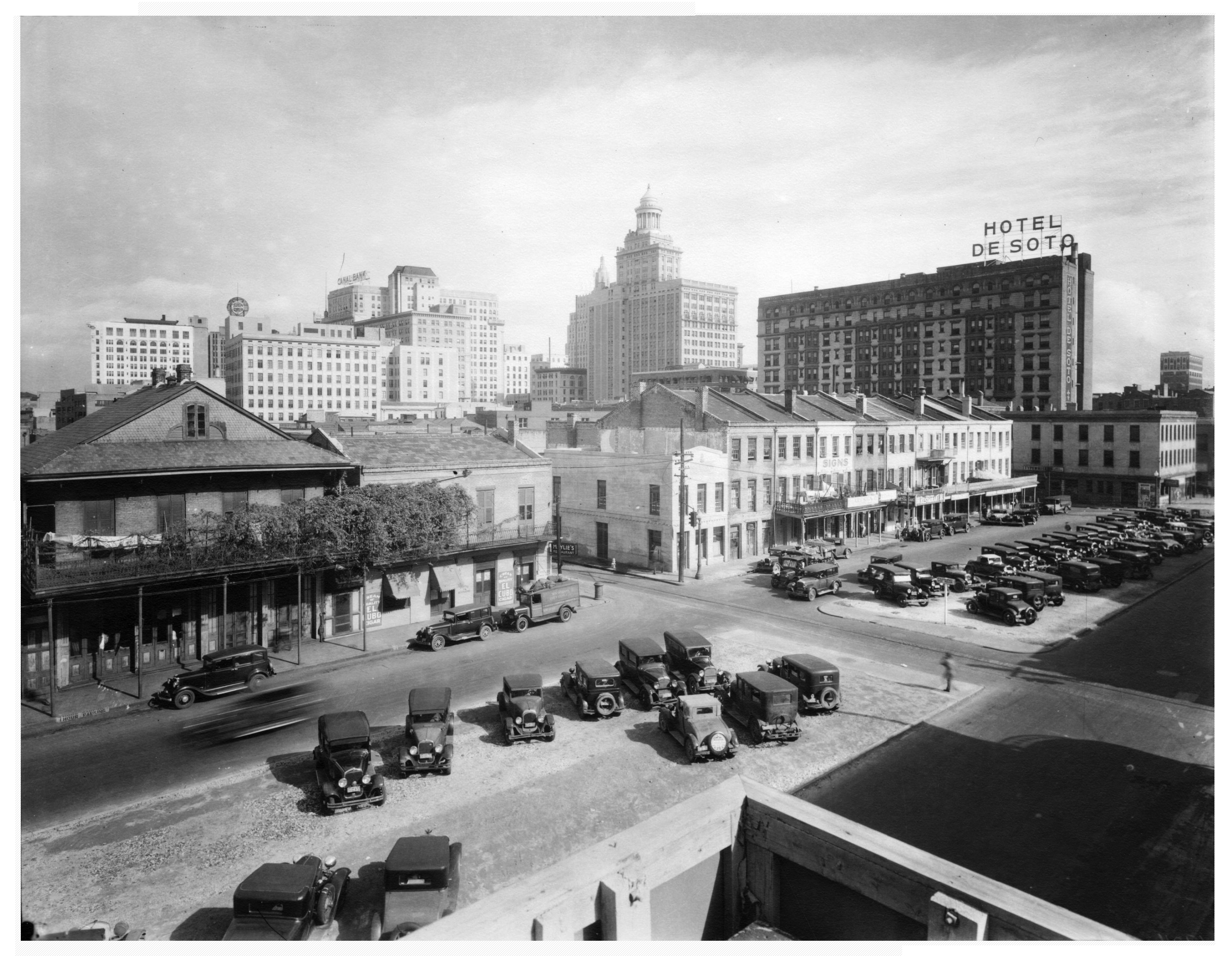 A black and white photo of a city street with a hotel sign reading 'HOTEL DE SOTO'.
