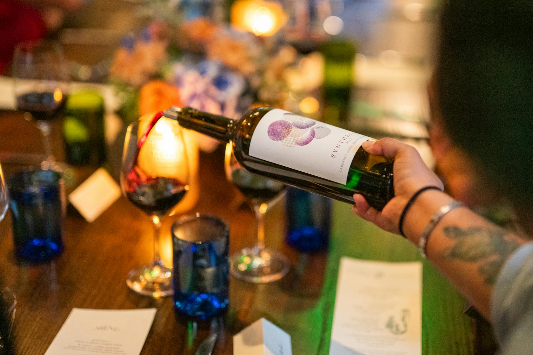 a person holding a bottle of wine on a table