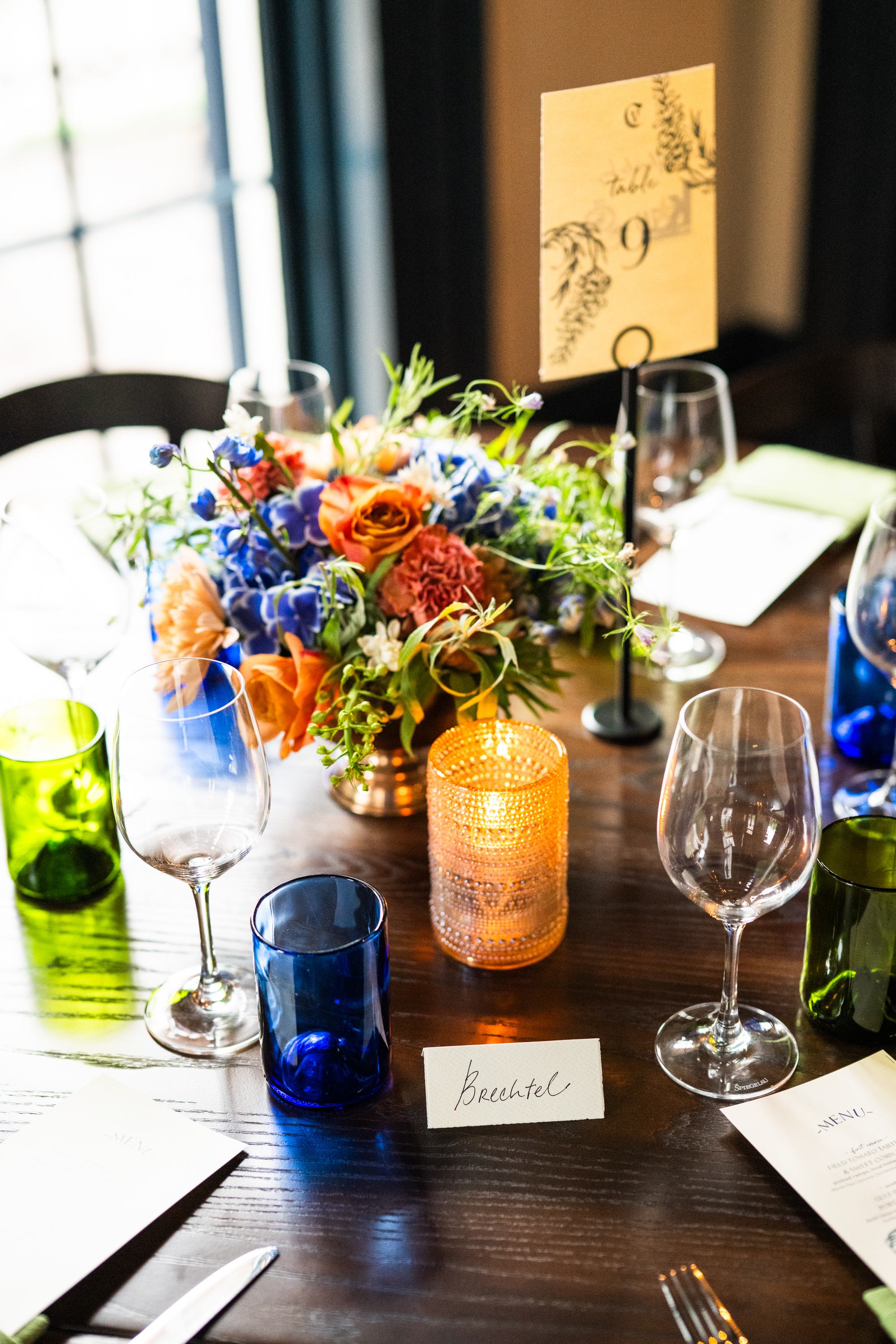 A dining table set with flowers, candles, and wine glasses.