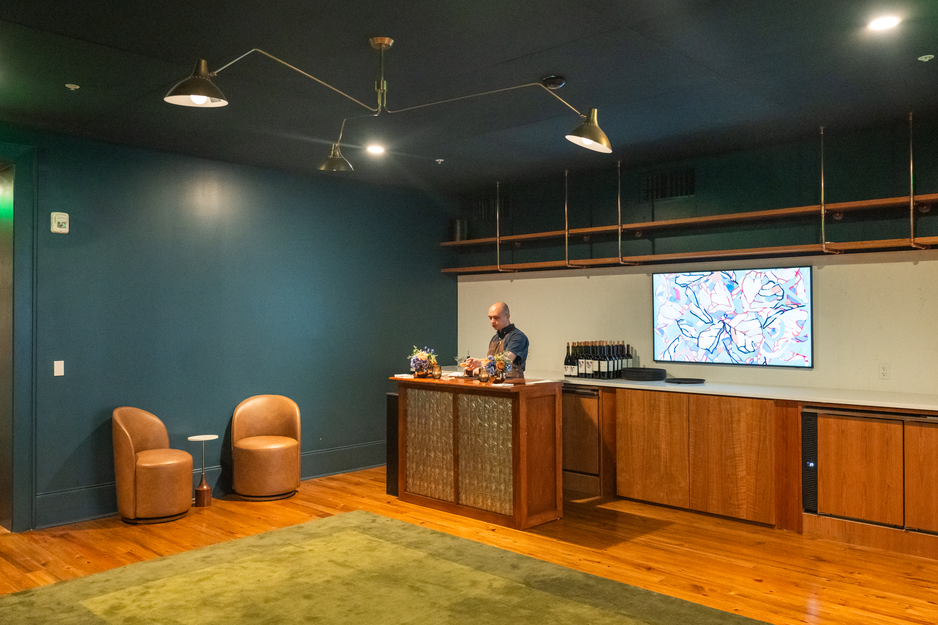 A hotel lobby with a bar, seating area, and TV on the wall.