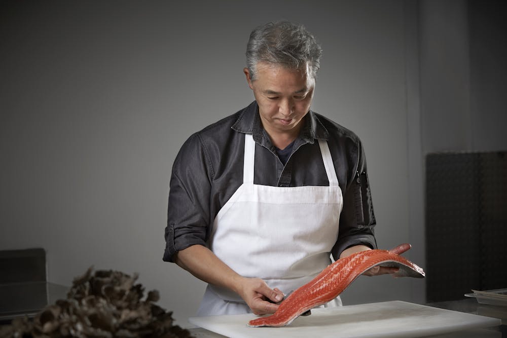 photo of Yo Matsuzaki, Executive Chef holding a piece of raw salmon