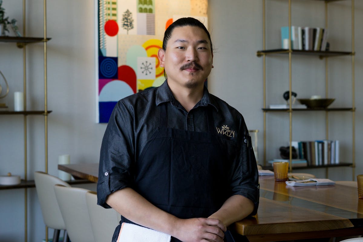 a male chef standing next to a table in the restaurant