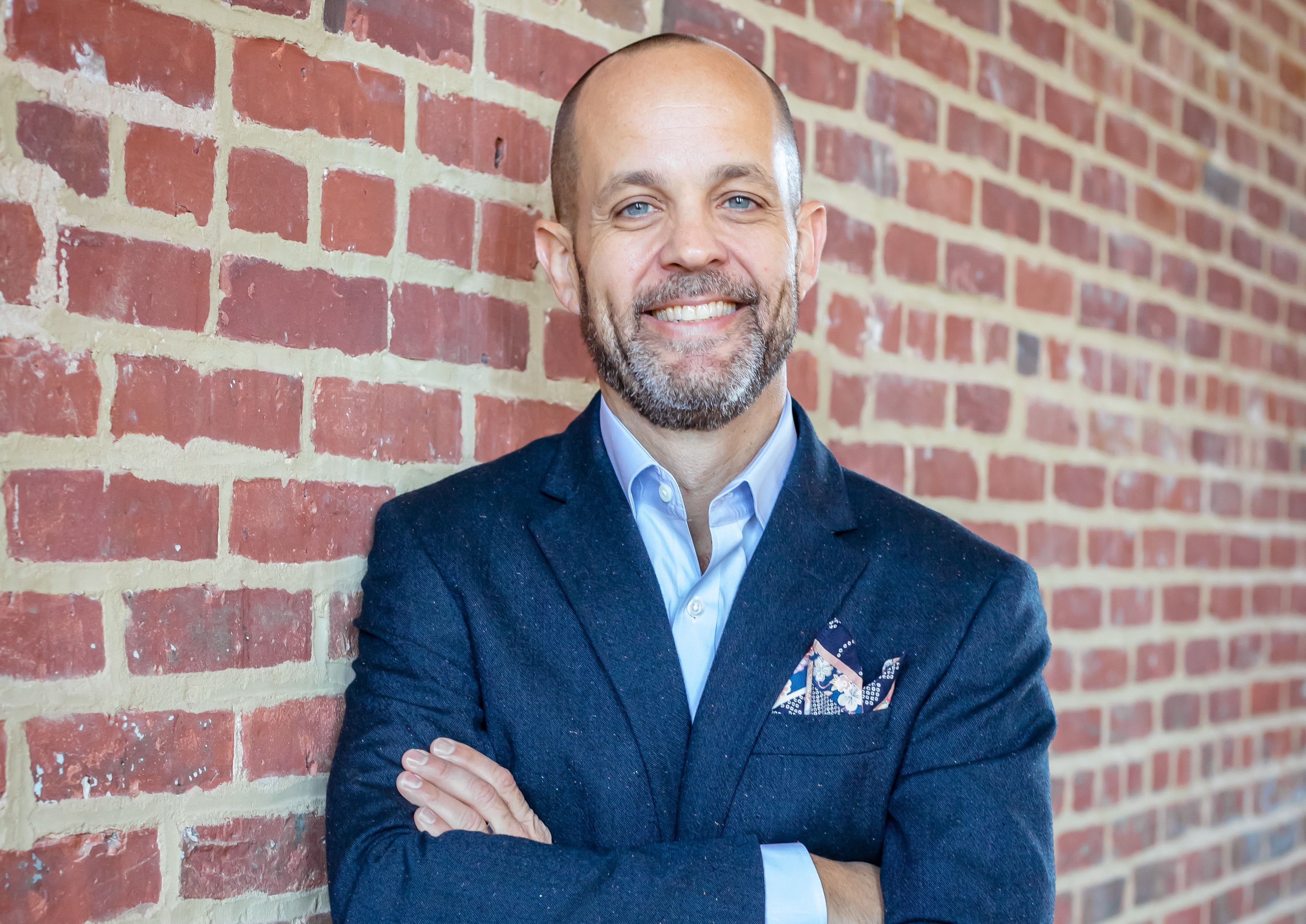 Professional headshot of Erik Bergman, Director of Restaurants and Bars, standing in front of brick wall as back-drop