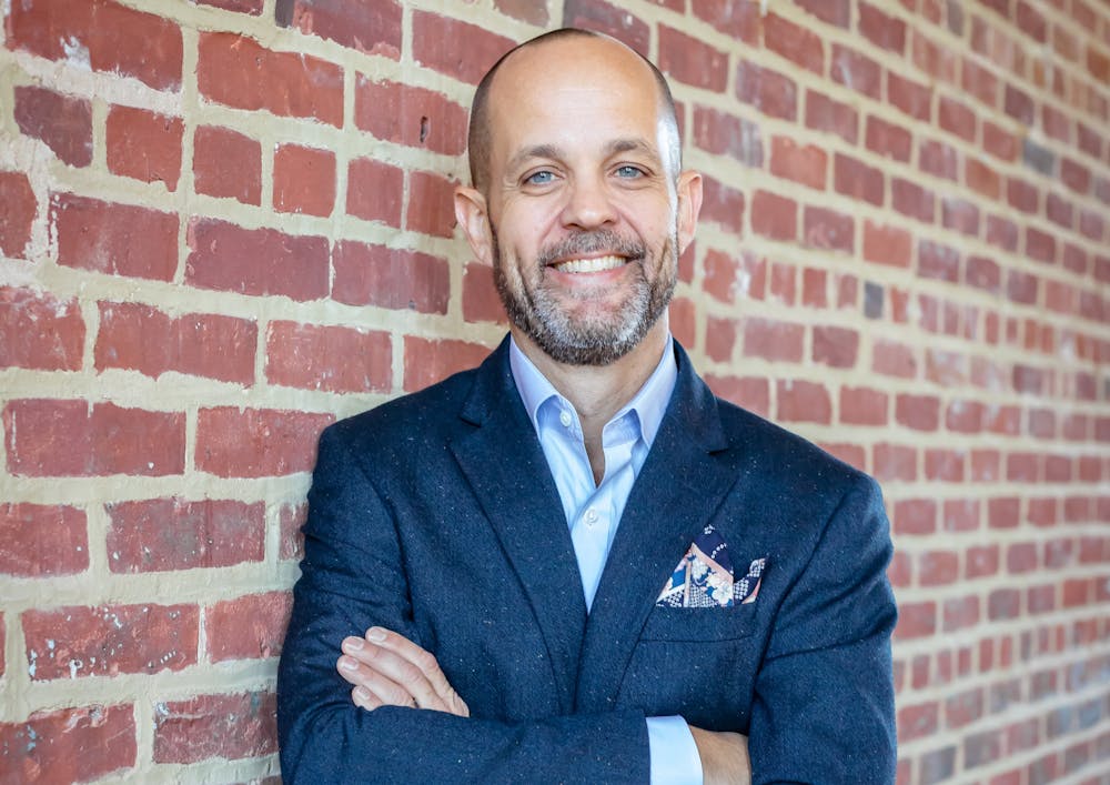 a man in a suit standing in front of a brick building