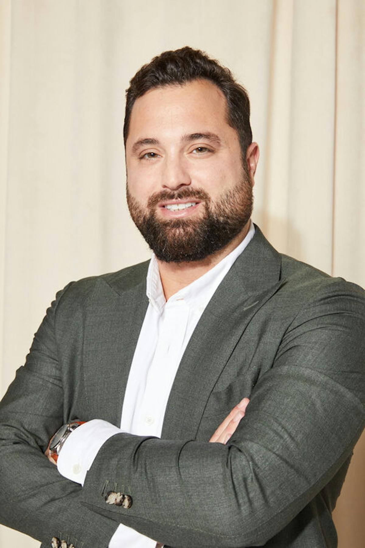 a man wearing a suit and tie smiling at the camera