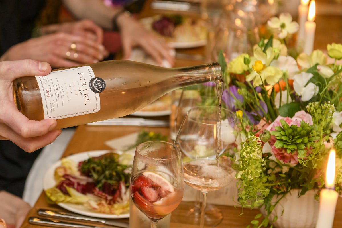 a person sitting at a table with food and wine