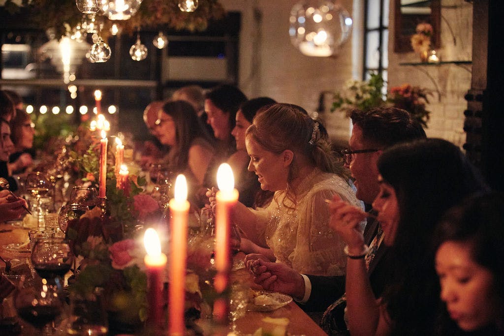 a group of people sitting in front of a birthday cake with lit candles