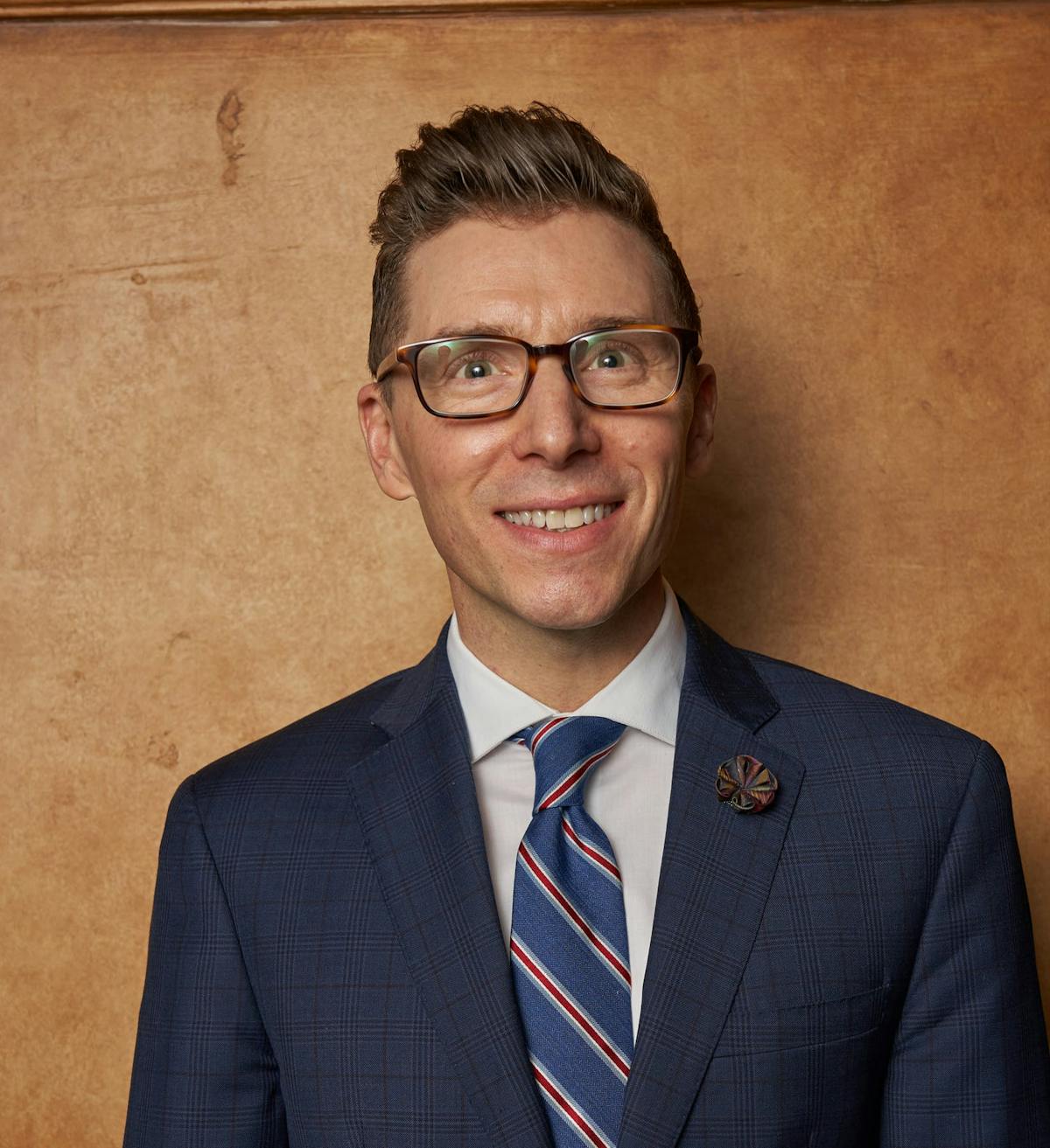 a man wearing a suit and tie smiling at the camera